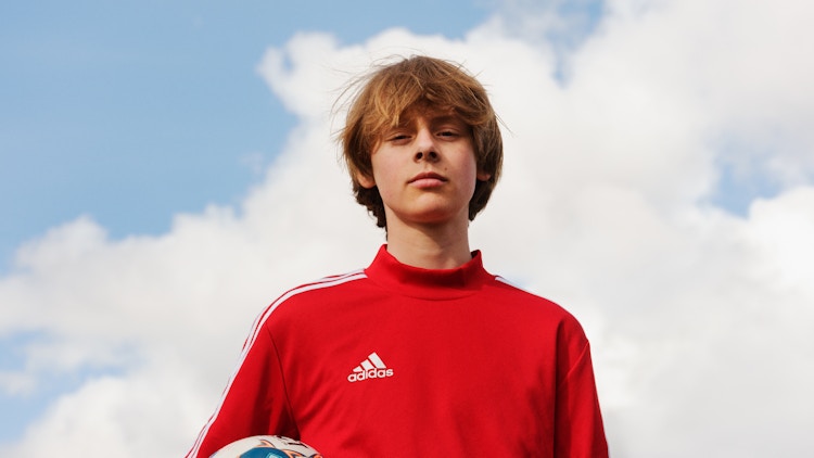 Barneombudet: ung gutt med himmel i bakgrunn. Fotball i hånden.