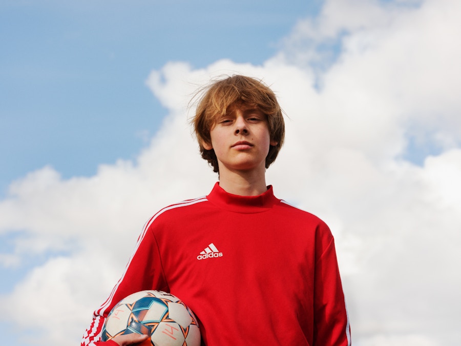 Barneombudet: ung gutt med himmel i bakgrunn. Fotball i hånden.