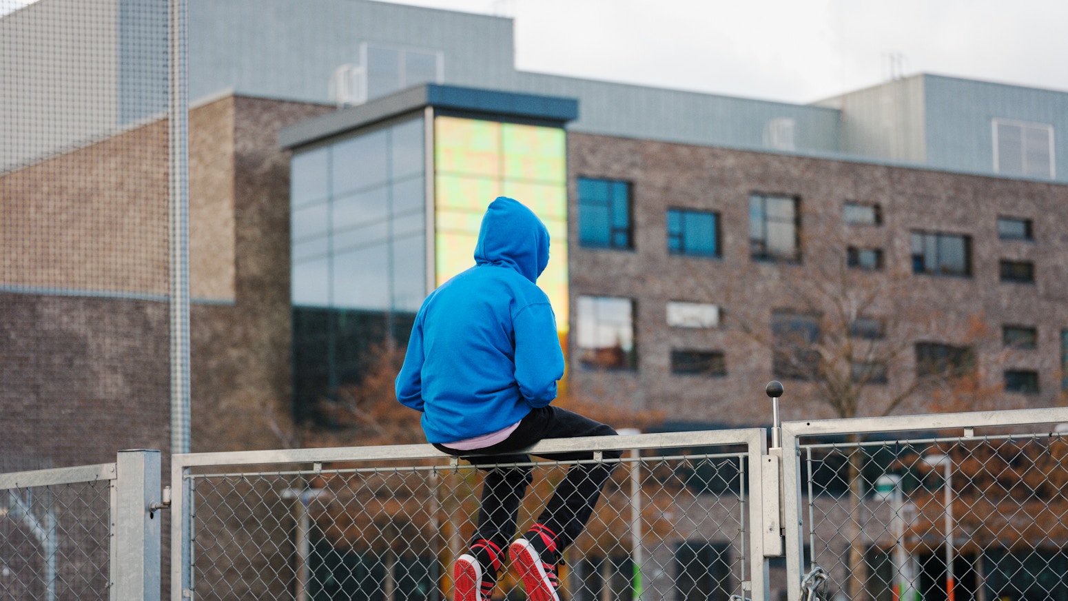Barneombudet: ungdom som sitter på et gjerde utenfor en bygning