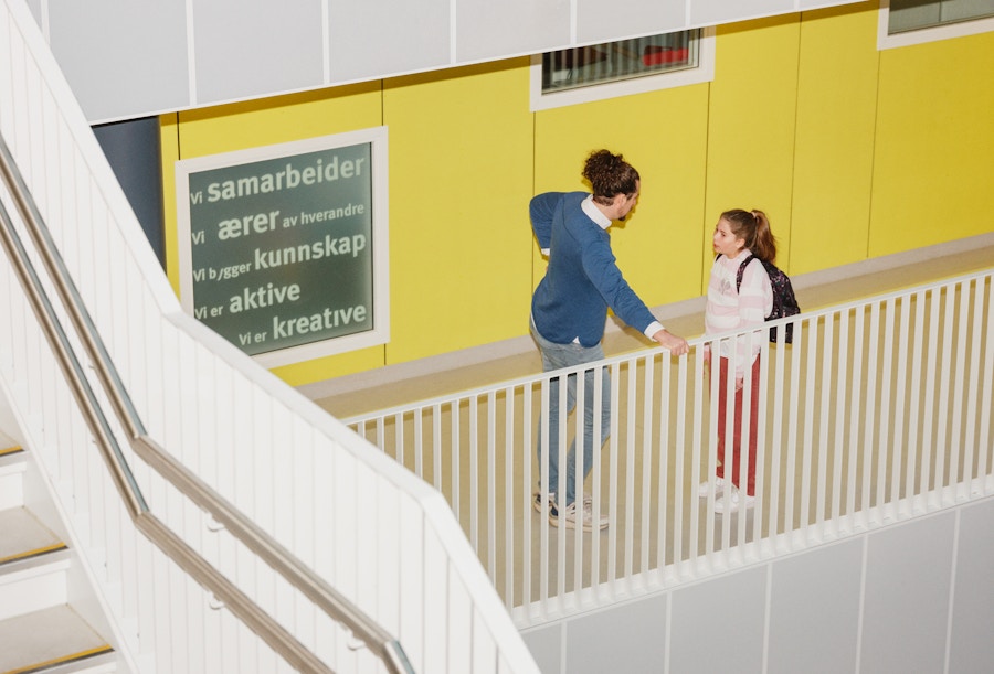 Barneombudet: voksenperson og ungdom som prater sammen i gangen på en skole