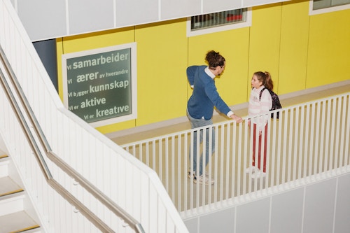 Barneombudet: voksenperson og ungdom som prater sammen i gangen på en skole