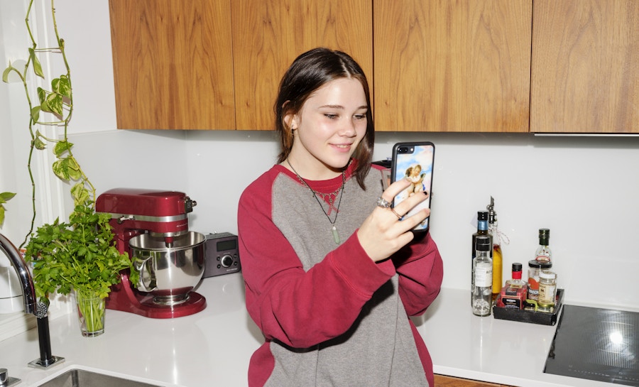 Barneombudet: jente på et kjøkken med telefon