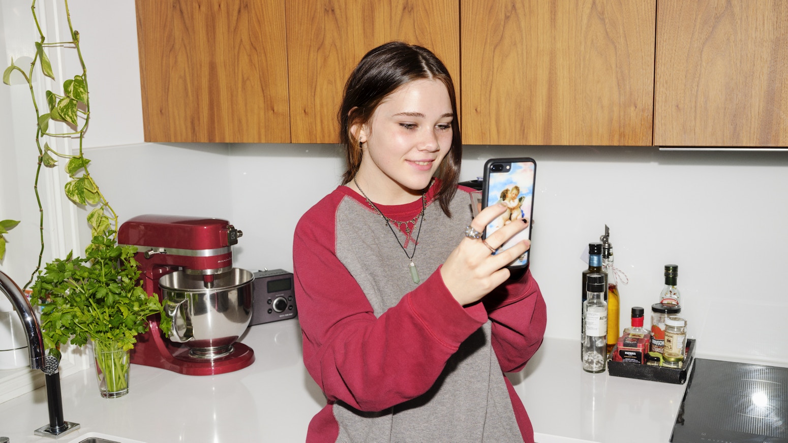 Barneombudet: jente på et kjøkken med telefon